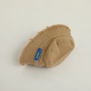 Vue détaillée du chapeau bob kaki avec bords effilochés et étiquette bleue 1607 XT en gomme