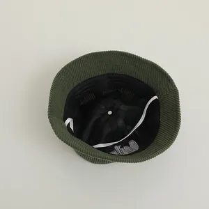 Detail of dark green corduroy bucket hat showing breathable mesh lining and windproof rope