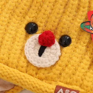 Gros plan d'un bonnet en tricot jaune avec visage de cerf mignon et étiquette en cuir
