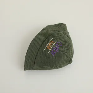 Detailed view of dark green corduroy bucket hat featuring vintage letter embroidery texture