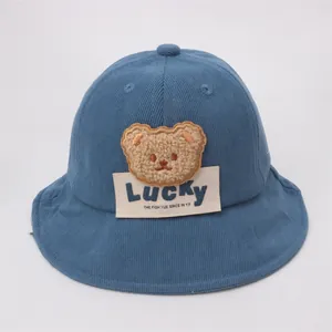 Dettaglio cappello neonato in velluto blu con toppa orsetto e cuciture curate