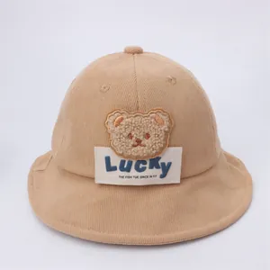 Dettaglio di un cappello pescatore in velluto a coste kaki con patch orso e etichetta Lucky