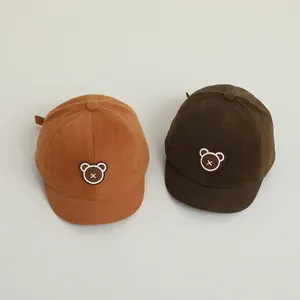 Detailed view of baby corduroy baseball caps with cute bear patches in yellow and brown