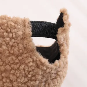 Detail of soft brown fleece hat featuring an adjustable black hook and loop fastener strap