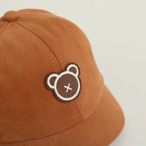 Detailed macro view of the bear embroidery patch on the brown corduroy baby baseball cap