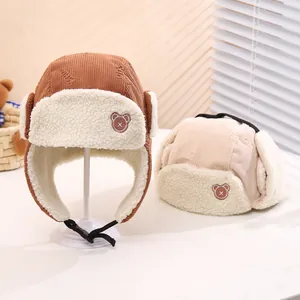 Detailed view of corduroy baby trapper hats with bear patches and soft faux fur lining