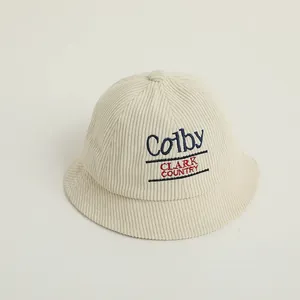 Macro detail of beige corduroy kids bucket hat with navy blue Colby letter embroidery