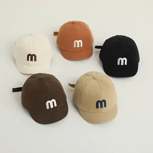 Detailed view of children's cotton baseball caps with letter M embroidery in five colors