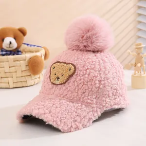 Detail of pink fleece baby baseball cap with teddy patch and large fluffy pompom ball
