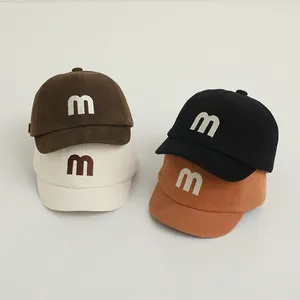 Detail of four colorful soft cotton baby baseball caps with embroidered m letter logo