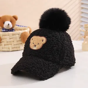 Detailed view of plush black winter cap featuring fluffy fur ball and cute bear embroidery