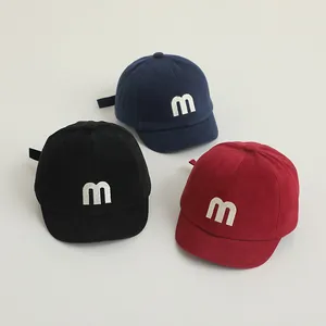 Detail of baby baseball caps in navy, black and red with embroidered white M letter