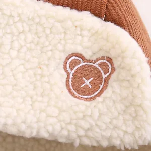 Detail of soft corduroy fabric and cute bear embroidery on children's winter trapper hat