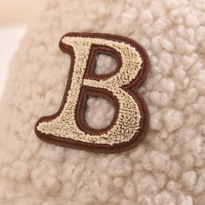 Detail des gestickten B-Patches auf der beigen flauschigen Teddyfell-Baseballkappe