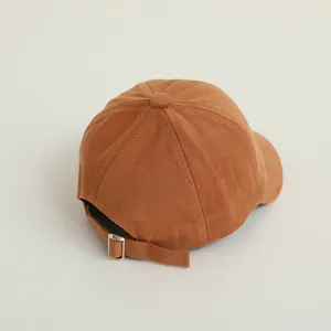 Close-up of the adjustable metal buckle and neat stitching on a brown cotton baseball cap