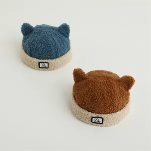 Detail of plush winter beanies with cute animal ears and M label in blue and brown