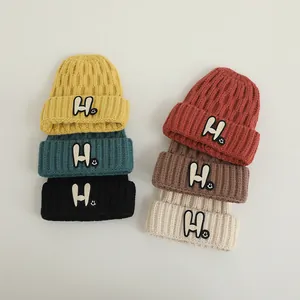 Detail of colorful knitted beanies showing soft thick textures and H-letter patches