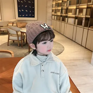 Close-up of brown knit beanie with leaf pattern and cute bunny patch on a toddler