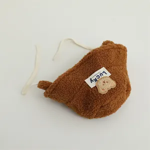 Detail of plush bear patch and Lucky label on brown winter teddy earflap hat
