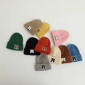 Vielfältige Farben der Strickmützen mit R-Buchstaben-Patch in flacher Auslage