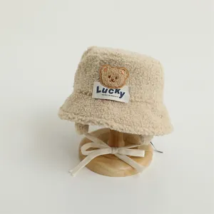 Detail of winter sherpa bucket hat featuring a brown bear patch and warm ear flaps