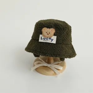 Close-up of deep green sherpa bucket hat with cute bear patch and Lucky label