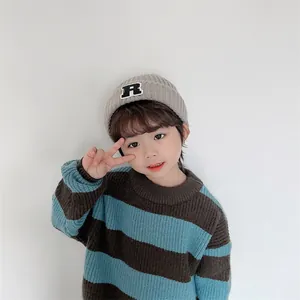 Nahaufnahme von gestreiftem Kinderstrickpullover und hellgrauer Mütze mit R-Aufnäher