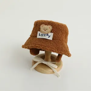 Detailed view of brown plush teddy bear bucket hat with Lucky label and chin straps
