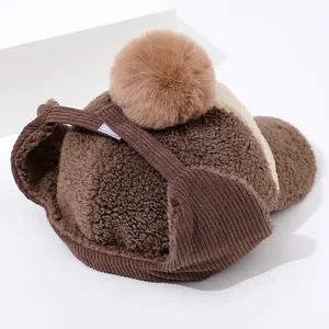 Detail of winter fleece trapper hat showing soft pom-pom and corduroy ear flaps