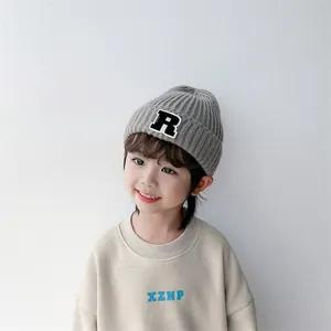Details von grauer Strickmütze mit R-Patch und beige Sweatshirt-Set für Kinder