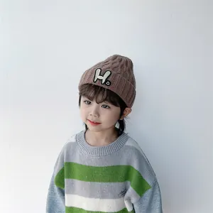 Detail of kids brown knit beanie featuring H letter and smiley face patch on cuffed brim