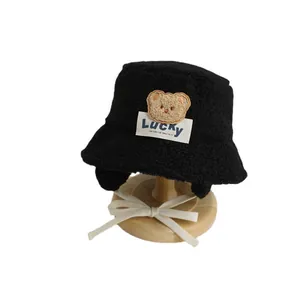 Winter plush black bucket hat for kids with bear patch and ear flaps for warmth