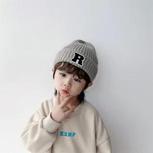 Kinder Strickmütze in Grau mit R-Aufnäher und beiges Sweatshirt für den Herbst