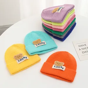 Posa piatta di berretti colorati in maglia con orsetti di peluche e toppe Lucky