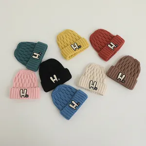 Close-up of knit winter beanies featuring embroidered H letter and smiley face detail