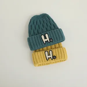 Kids' winter knit beanies in forest green and ginger yellow with H letter embroidery