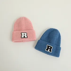 Detail von rosa und blauen Rippstrickmützen mit weißen R-Buchstaben-Patches