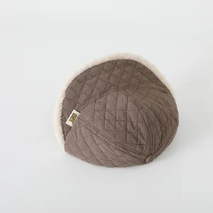 Dettaglio cappello invernale trapuntato con fodera in pile bianco e motivo a rombi