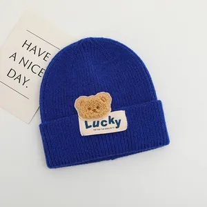 Dettaglio berretto in maglia blu navy con orsetto di peluche ed etichetta Lucky
