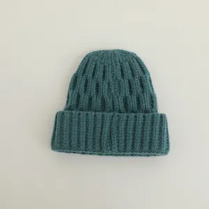 Detailed macro view of the dark teal knit texture and folded cuff on the winter beanie