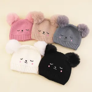 Detailed view of knitted baby hats with double pom-poms and cute animal face embroidery