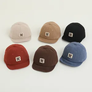 Detail view of corduroy baseball caps in six colors with a minimalist 'K' logo patch