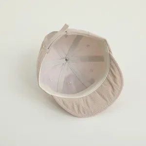 Detailed interior of corduroy baby cap showing white sweatband and adjustable strap