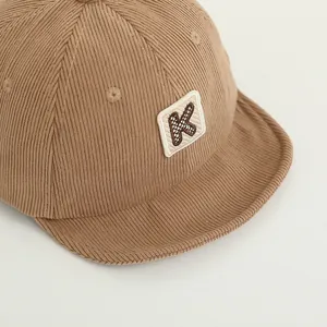 Macro detail of khaki corduroy texture and embroidered K letter on a child baseball cap