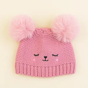 Detailed view of pink knitted baby hat with two large pom-poms and cute animal embroidery