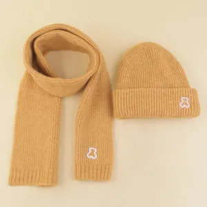 Detailed knit texture of ginger children scarf and beanie set with cute bear embroidery