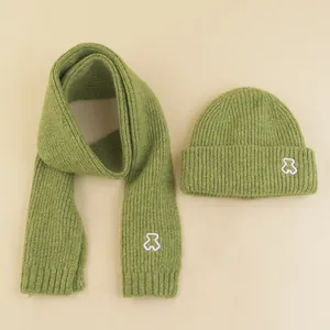 Detailed view of green knitted scarf and hat set with white bear embroidery