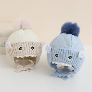 Détail de bonnets d'hiver pour bébé avec matelassage, pompons et broderie mignonne