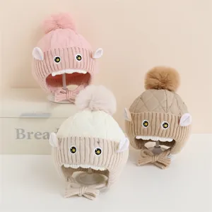 Détail de trois bonnets d'hiver pour enfants avec protège-oreilles en rose, beige et kaki