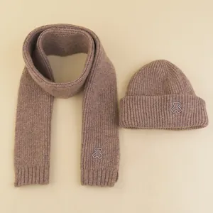 Detailed view of brown knit hat and scarf set with cute embroidered bear design